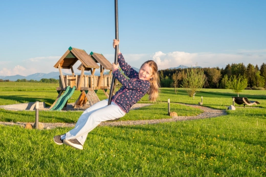Mädchen auf Seilbahn, im Hintergrund großer Spielplatz