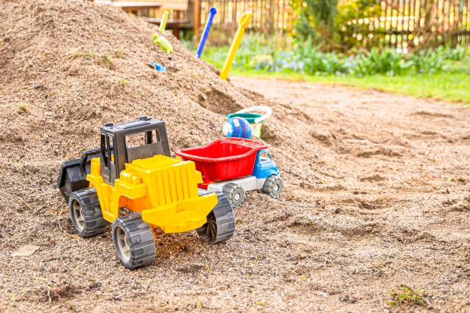 Sandkastenspielzeug, Traktor und Schaufeln im Sand