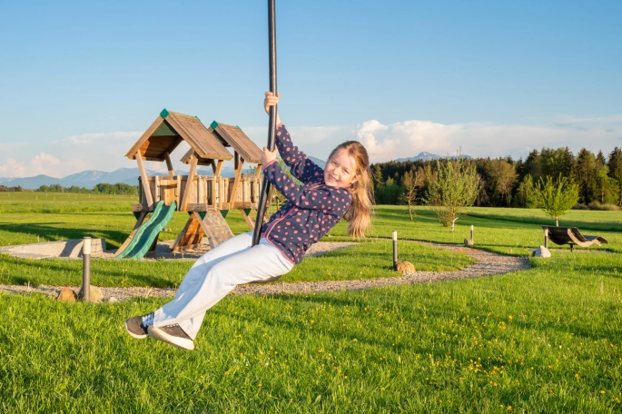 Mädchen auf Seilbahn, im Hintergrund großer Spielplatz