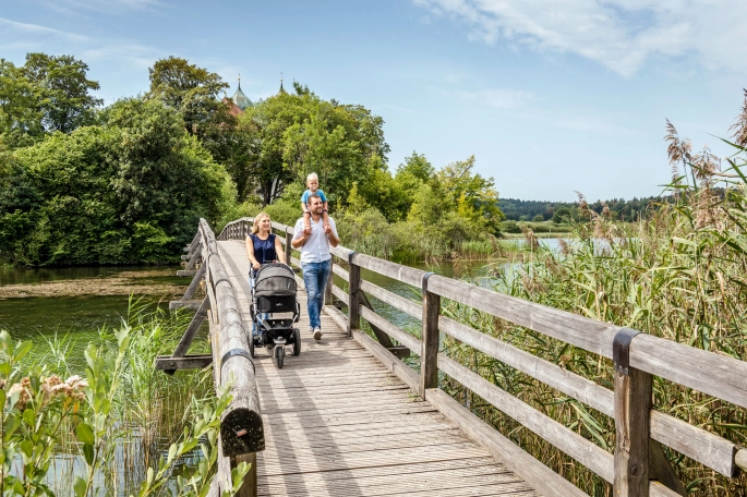 Familie die über eine Brücke mit Kinderwagen fährt